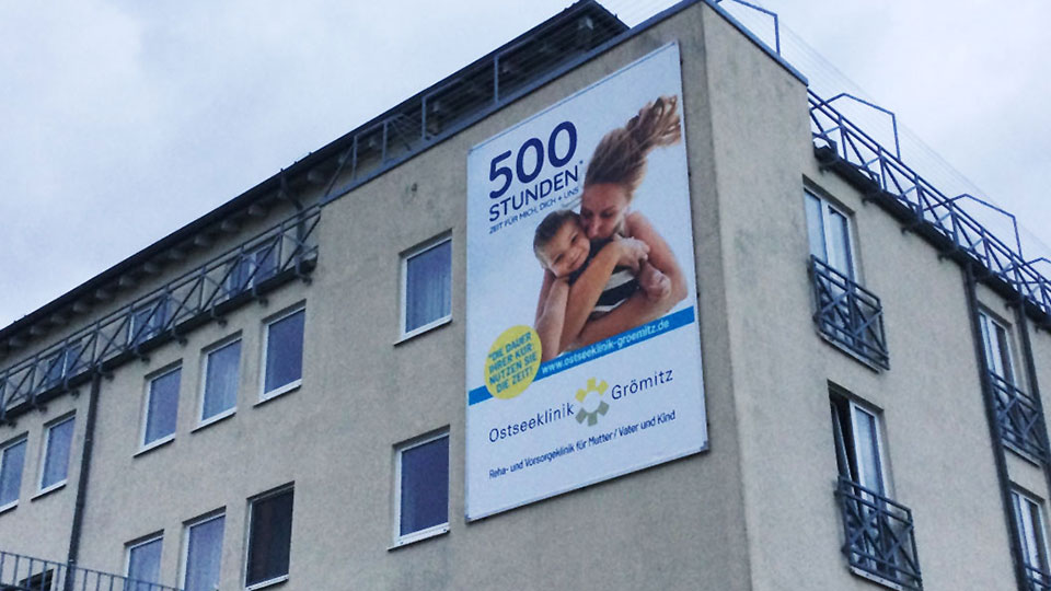 Nahaufnahme der Fassade der Klinik mit der neuen Werbeanlage mit dem Kederrahmen+