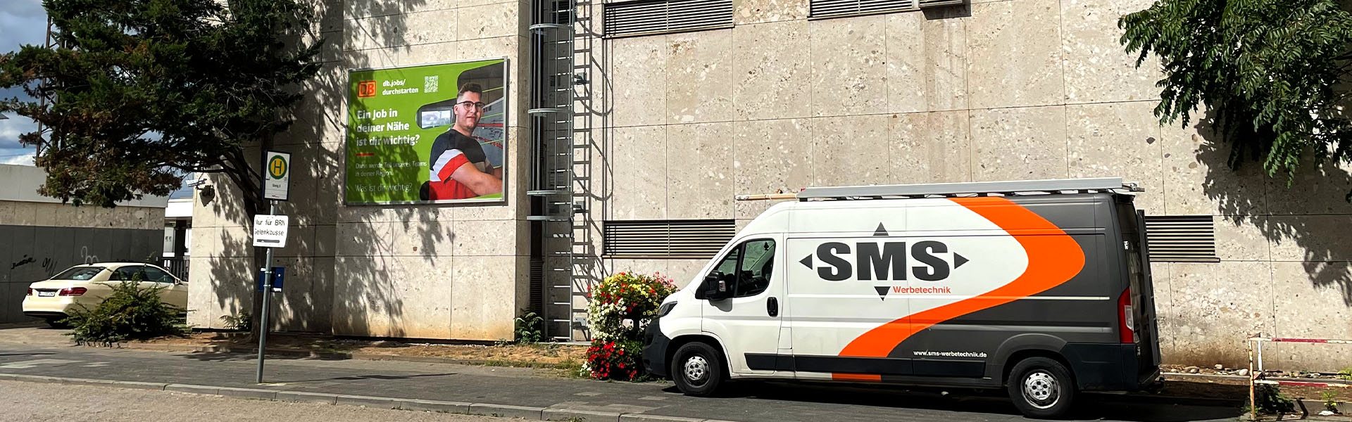 Fassadenwerbung Hauptbahnhof Frankenthal mit dem Kederrahmen+ für die Deutsche Bahn. Ansicht aus einer mittlerenEntfernung mit SMS | Werbetechnik Firmenfahrzeug