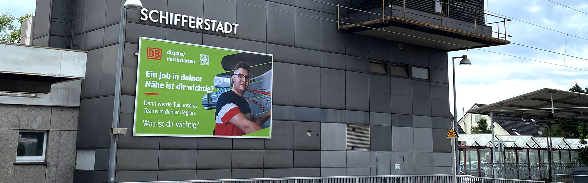 Befestigung einer Fassadenwerbung am Bahnhof Schifferstadt mit dem Kederrahmen+ für die Deutsche Bahn. Ansicht von der linken Seite.