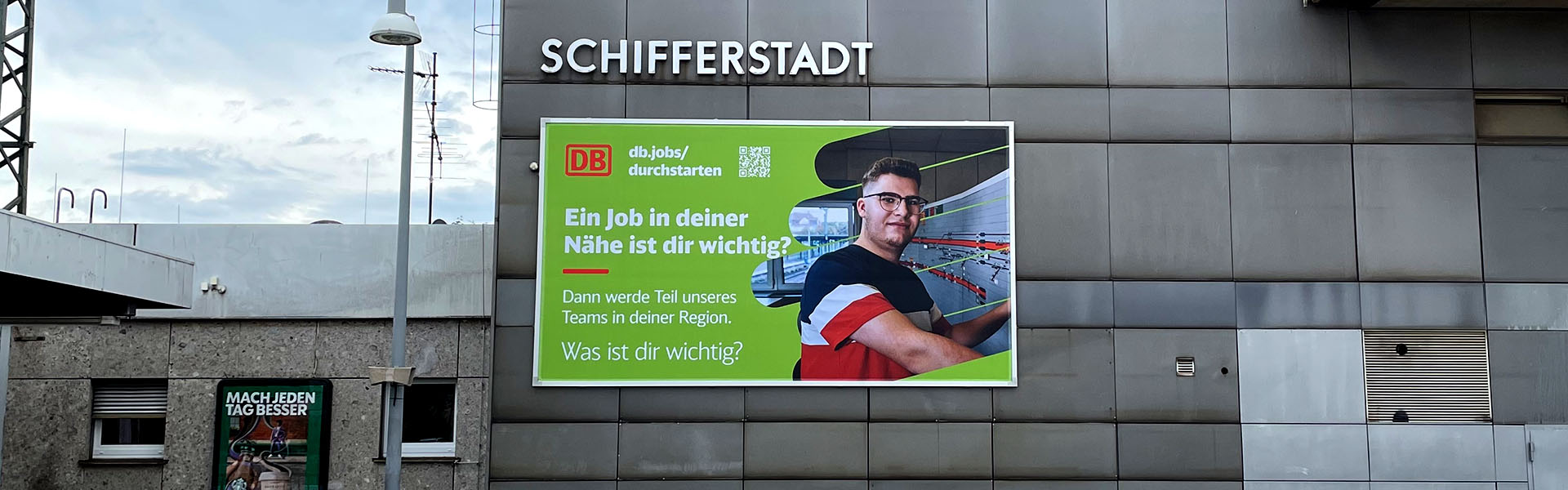Frontansicht der Befestigung einer Fassadenwerbung am Bahnhof Schifferstadt mit dem Kederrahmen+ für die Deutsche Bahn.