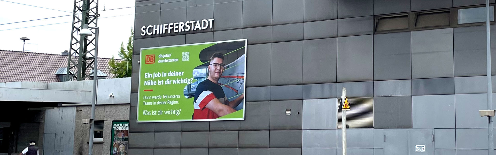 Befestigung einer Fassadenwerbung am Bahnhof Schifferstadt mit dem Kederrahmen+ für die Deutsche Bahn. Ansicht von der rechten Seite.