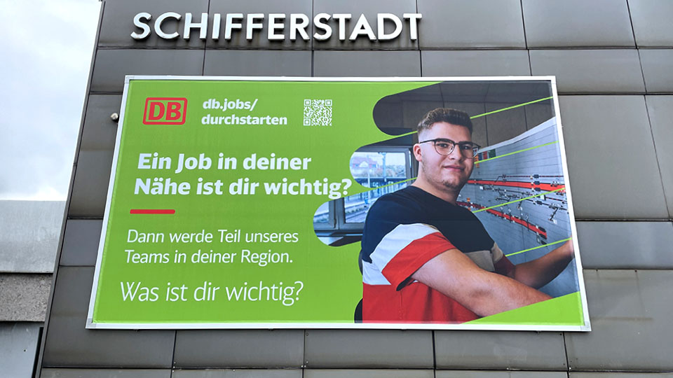 Frontansicht der Befestigung einer Fassadenwerbung am Bahnhof Schifferstadt mit dem Kederrahmen+ für die Deutsche Bahn.