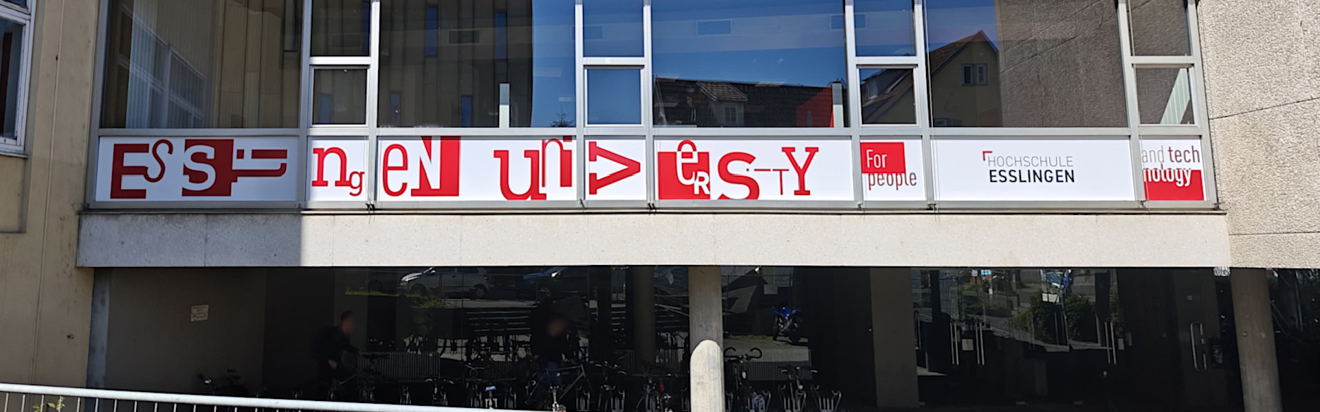 Beschriftung mit Folien am Gebäudedurchgang der Hochschule. Frontansicht.